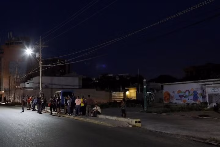 Người dân đợi xe bus ở Maracaibo vào ngày 26/7. Thành phố này từng nổi tiếng với các cuộc tiệc tùng thâu đêm. Nay nơi đây về đêm thường chìm trong bóng tối mịt mùng.
