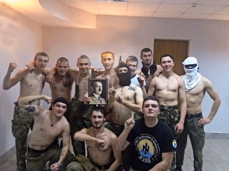 Một chiến binh của Tiểu đoàn Azov (đứng giữa) nâng niu bức ảnh của trùm phát xít Hitler.