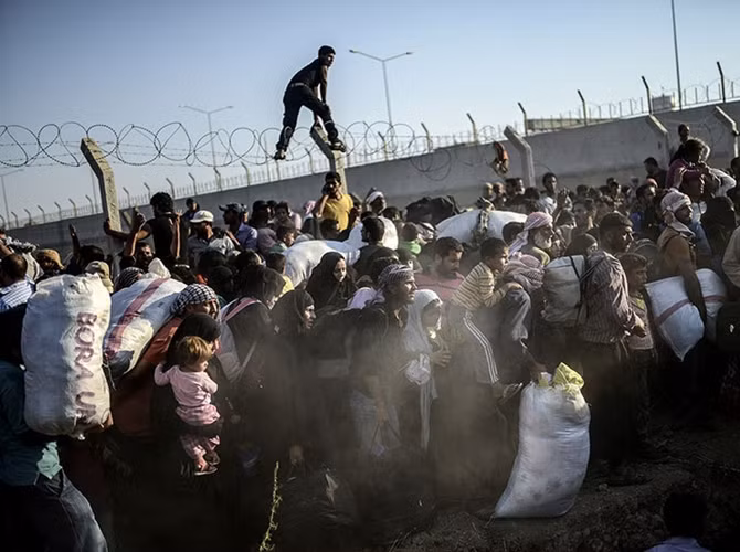 Người tị nạn Syria leo qua rào dây thép gai chạy sang Thổ Nhĩ Kỳ.