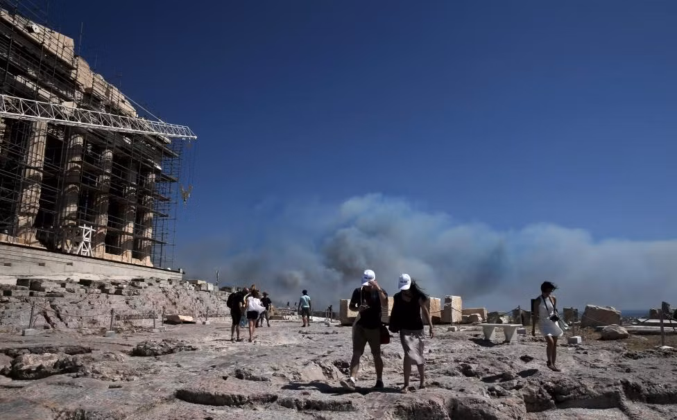Du khách ở Đền Parthenon lo lắng nhìn khói bụi bao trùm thủ đô Athens ngày 17/7/2015.