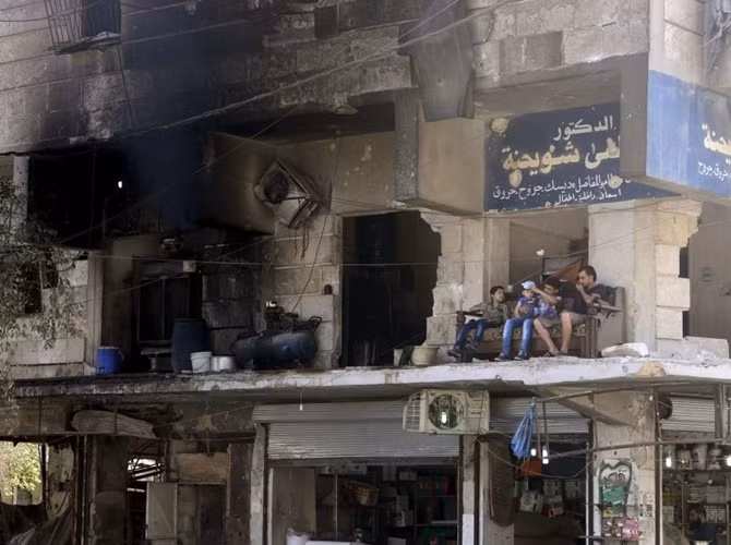 Người dân địa phương trên ban công một ngôi nhà bị chiến tranh tàn phá ở Aleppo, thành phố lớn nhất Syria.