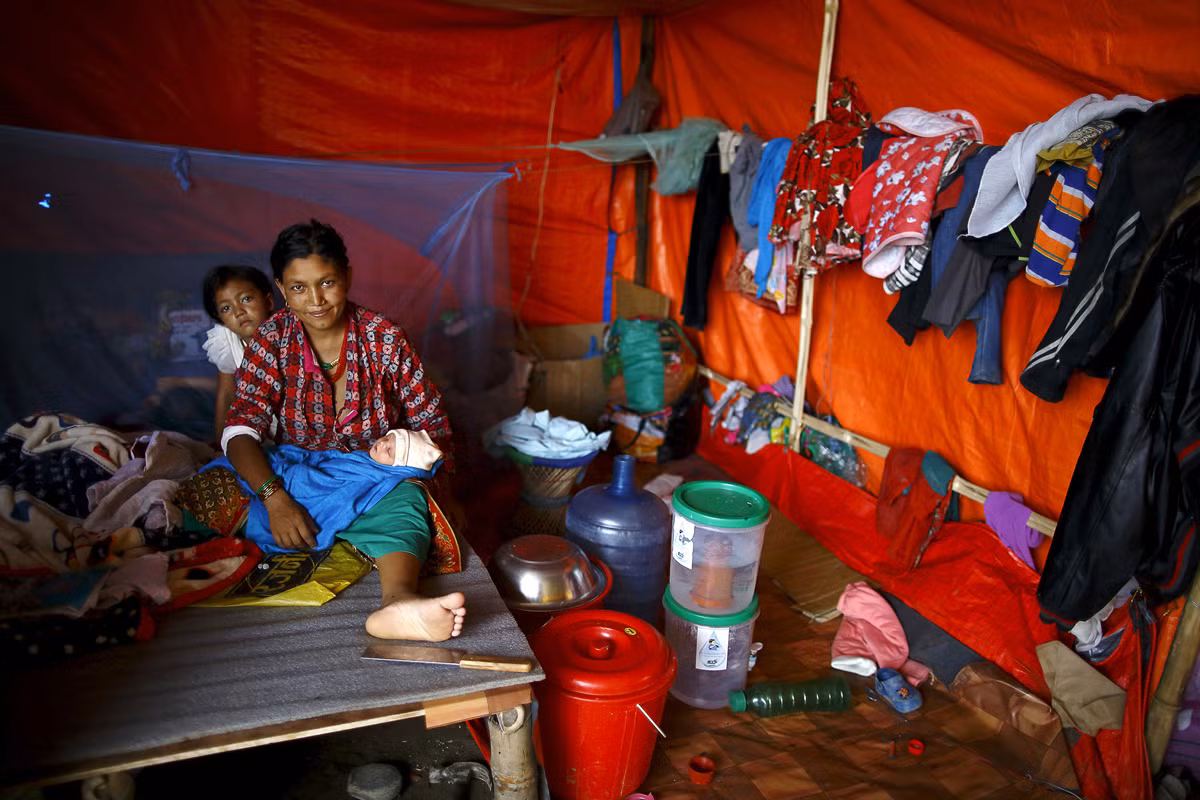 Người phụ nữ cùng hai con sống trong túp lều tạm bợ ở Kathmandu ngày 8/7/2015.