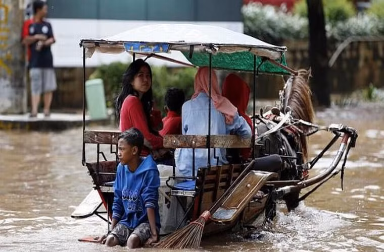 Người dân ngồi trên xe ngựa kéo để di chuyển sau khi những cơn mưa lớn gây ngập lụt nhiều khu vực của thành phố Jakarta ngày 10/2/2015.