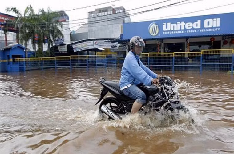Người đàn ông này đang cố gắng điều khiển chiếc xe máy băng qua dòng nước ở thủ đô Jakarta ngày 10/2/2015.