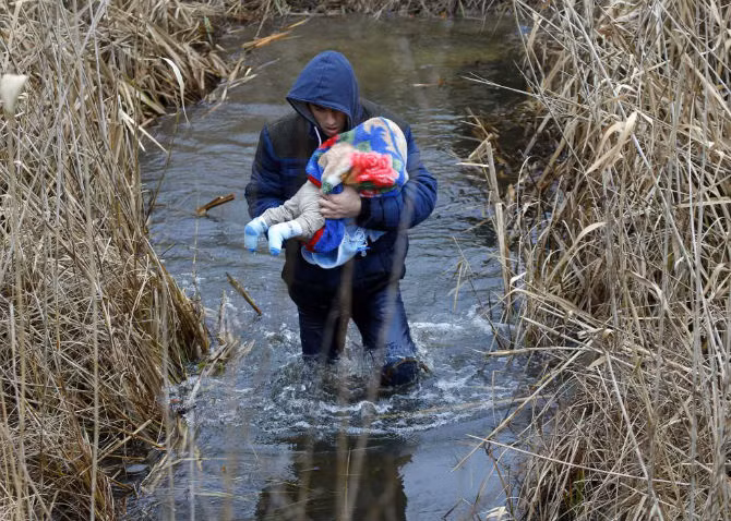 Một người đàn ông Kosovo bế con nhỏ trên tay vượt biên giới Hungary – Serbia ngày 6/2/2015.