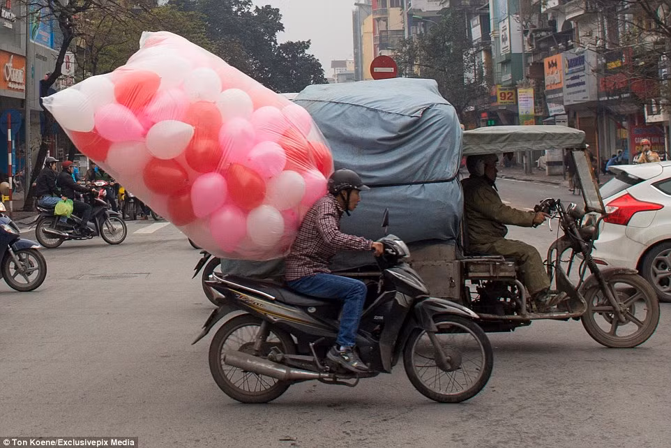 Một túi bóng khổng lồ sau lưng người đàn ông đang điều khiển chiếc xe máy trên đường phố Việt Nam.