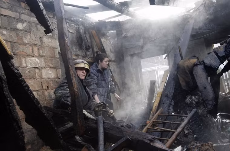 Người phụ nữ và lính cứu hỏa đi qua đống đổ nát của ngôi nhà trong khu dân cư bị phá hủy do đạn pháo ở Donetsk ngày 3/2/2015.