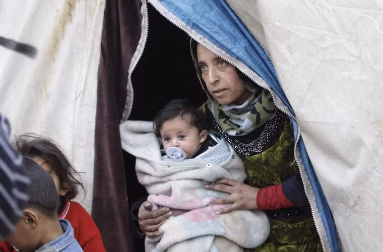 Người phụ nữ bế 1 đứa trẻ trong khu trại tị nạn Al-Karameh giáp biên giới Syria-Thổ Nhĩ Kỳ ở phía bắc thành phố Idlib, Syria ngày 10/1/2015. 