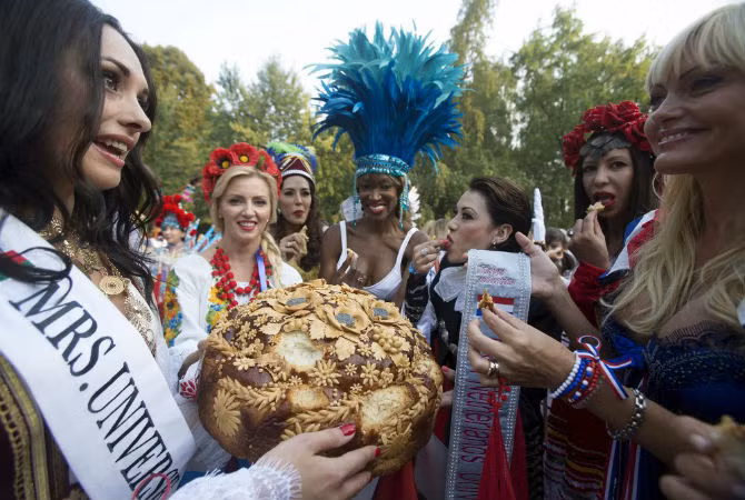 Các thí sinh dự thi Mrs.Universe 2015 trong chuyến thăm Thảo Cầm Viên ở thủ đô Minsk, Belarus. Người dân ở đây chào đón họ với bánh mỳ và muối, hai món ăn truyền thống thể hiện lòng hiếu khách.