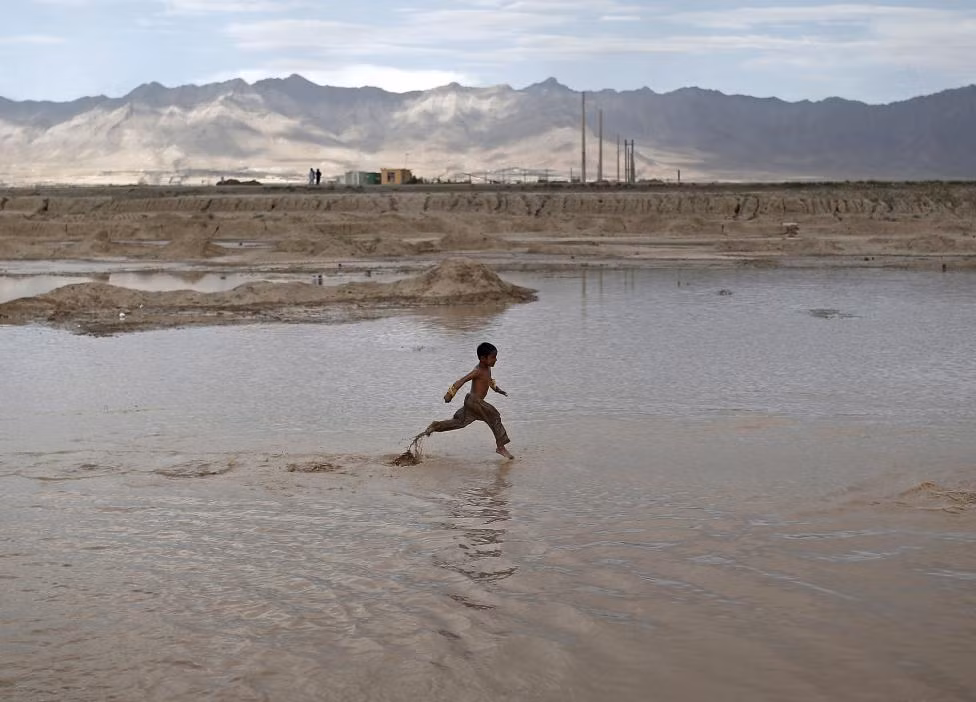 Một bé trai đùa nghịch dưới nước ở vùng ngoại ô thành phố Kabul, Afghanistan, ngày 30/7.