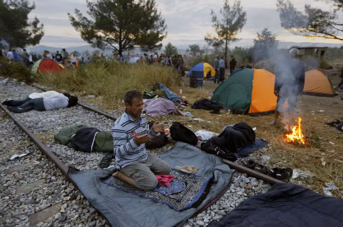 Một di dân Syria cầu nguyện ở đường tàu tại làng Idomeni, biên giới Hy Lạp – Macedonia ngày 22/8.