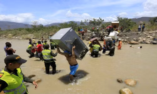 Hàng trăm người dân Colombia mang theo đủ thứ đồ như tủ lạnh, chiếu, quạt điện, gà vịt, dê,...vượt sông.