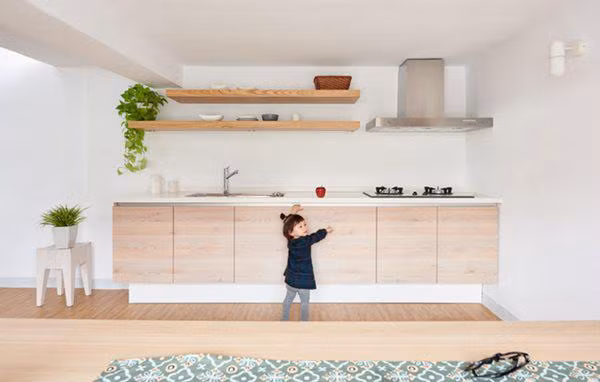 Khu vực bếp nằm ngay dưới gác lửng, bàn ăn được đặt cạnh khung cửa sổ lớn, chiếm gần trọn vẹn bức tường đối diện bếp. Căn bếp nhỏ gọn gàng luôn ngập tràn ánh sáng nhờ khung cửa sổ lớn này.