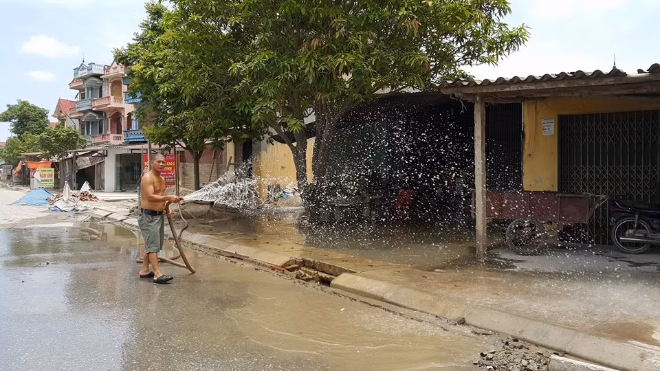Nhiều hộ dân đã phải ra tưới nước giữa trời nắng nóng nhưng tình trạng bụi không thuyên giảm.