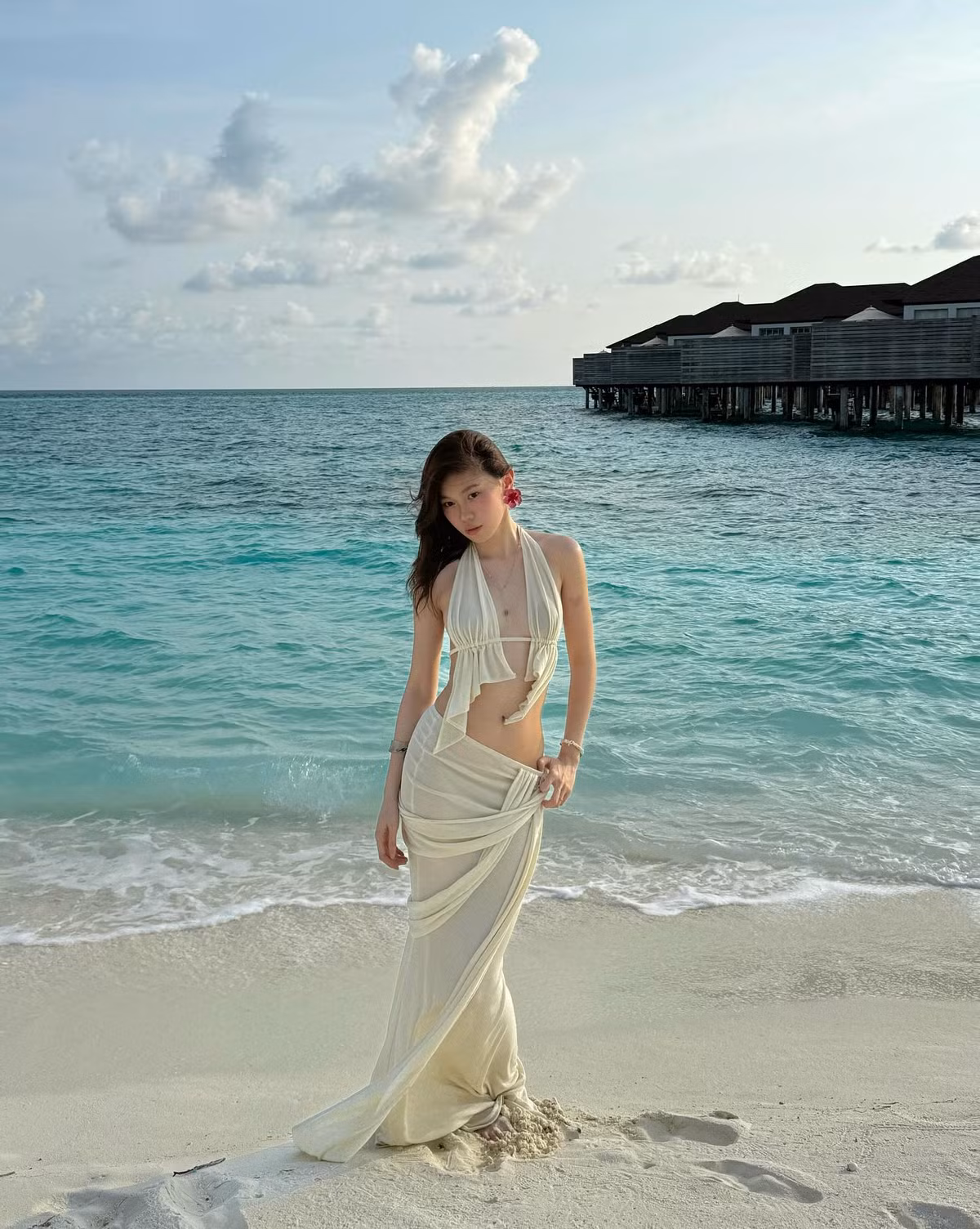 Trước đó, Ly Phạm diện một set đồ biển màu kem nhã nhặn nhưng đầy phá cách, gồm áo yếm cách điệu khoe lưng trần nuột nà, kết hợp cùng chân váy quấn hờ tinh tế, tạo nên tổng thể vừa mềm mại, vừa gợi cảm.
