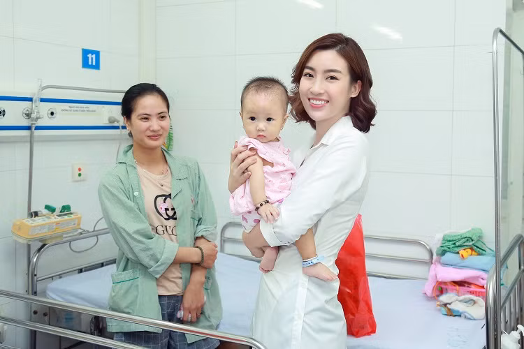 Hoa hậu Đỗ Mỹ Linh bế một em nhỏ trong bệnh viện.