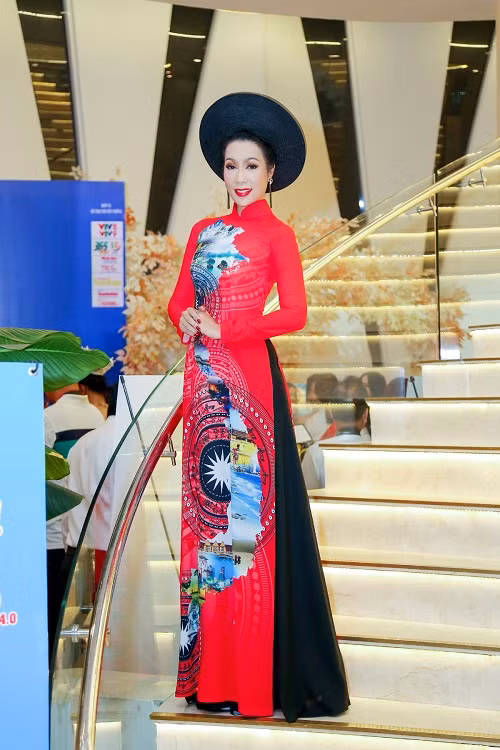 Trang phục áo dài màu đỏ rực với họa tiết trống đồng giúp Trịnh Kim Chi vô cùng nổi bật.