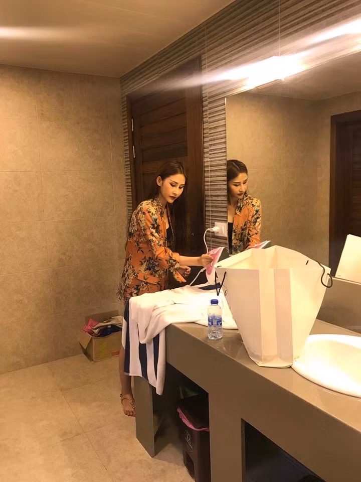 Chi Nguyễn tranh thủ đứng ủi đồ trong nhà vệ sinh.
