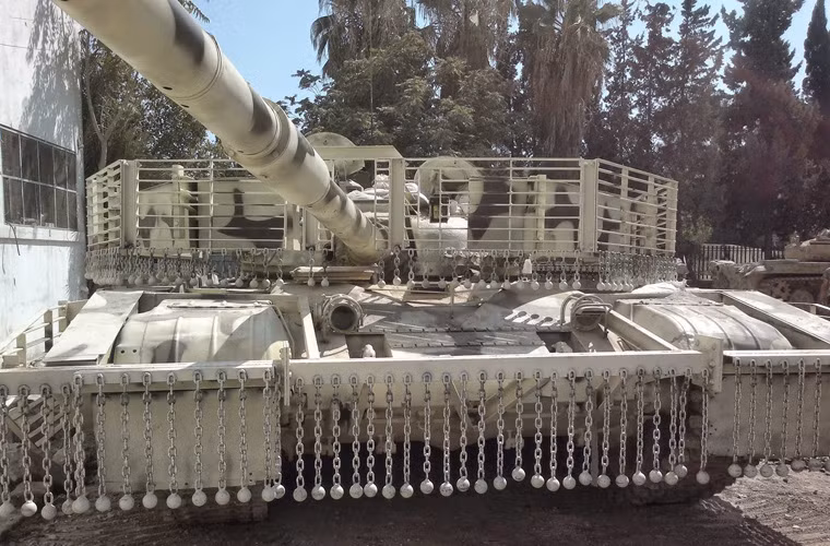 Còn đây là một chiếc T-72 gắn thêm diềm xích che gầm, che xích hai bên hông, lồng thép quanh tháp pháo. Nguồn ảnh: SouthFront